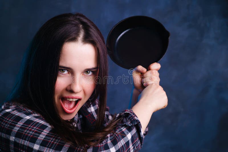 Galen ung hemmafrukvinna som svänger med en panna Matlagning culina royaltyfri fotografi Galen ung hemmafrukvinna som svänger med en panna Matlagning culina royaltyfri fotografi