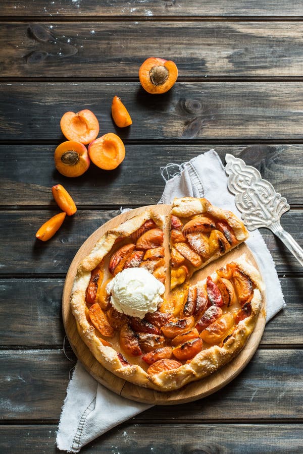 Galette fait maison d'abricot fait avec les apricotes organiques frais sur la table en bois, vue supérieure Processus de la cuisson Tarte ouvert, tarte d'abricot Boulangerie de fruit Crème glacée froide avec le tarte chaud