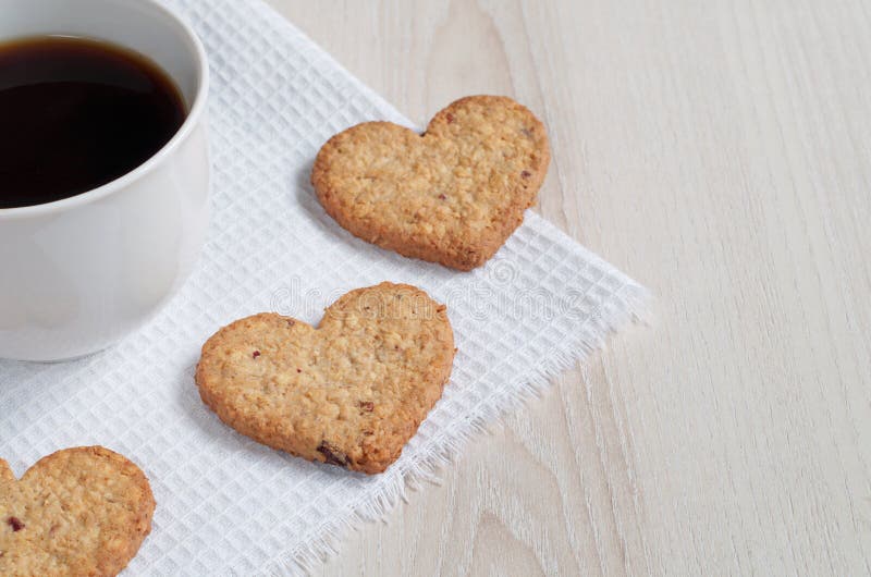 Galletas de harina de avena en forma de corazón y una taza de café imagen de archivo Galletas de harina de avena en forma de corazón y una taza de café imagen de archivo