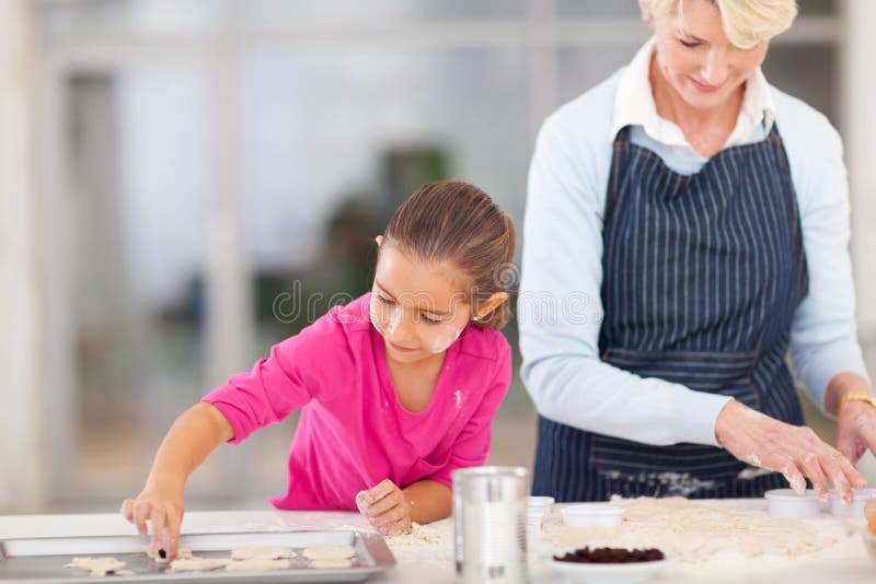 Senior grandmother baking cookies with granddaughter in kitchen. Senior grandmother baking cookies with granddaughter in kitchen