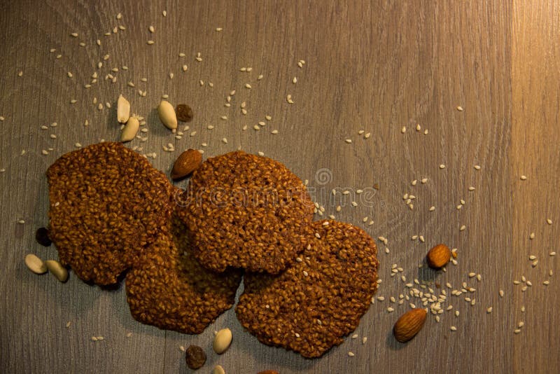 Galletas hechas en casa con las semillas de sésamo en una pizarra y en un fondo oscuro foto de archivo Galletas hechas en casa con las semillas de sésamo en una pizarra y en un fondo oscuro foto de archivo