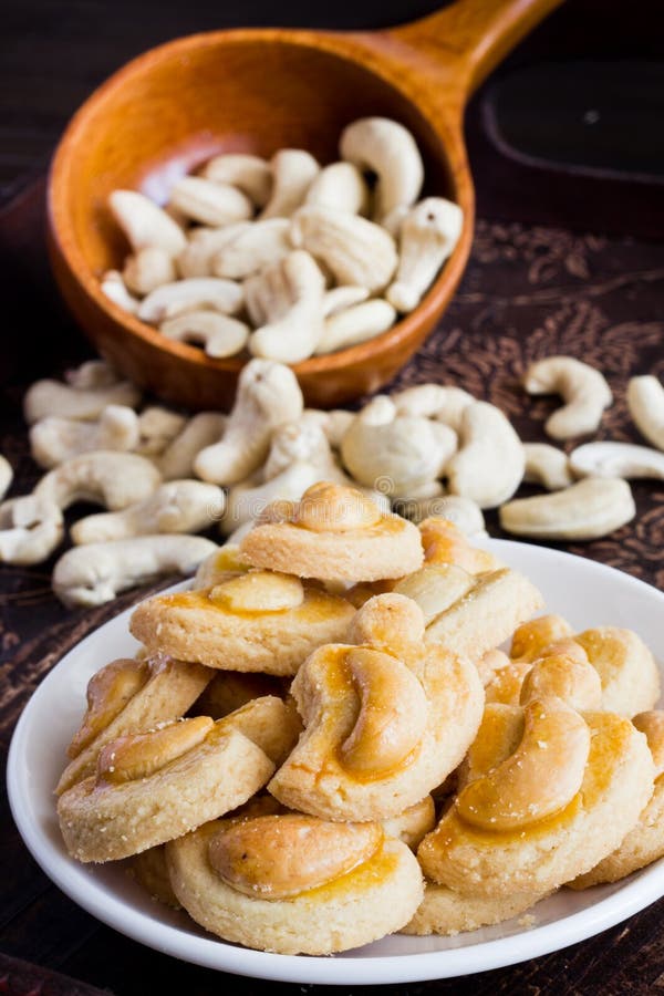 Traditional Cashew Nut Cookies on white plate with raw cashew nuts background. Traditional Cashew Nut Cookies on white plate with raw cashew nuts background