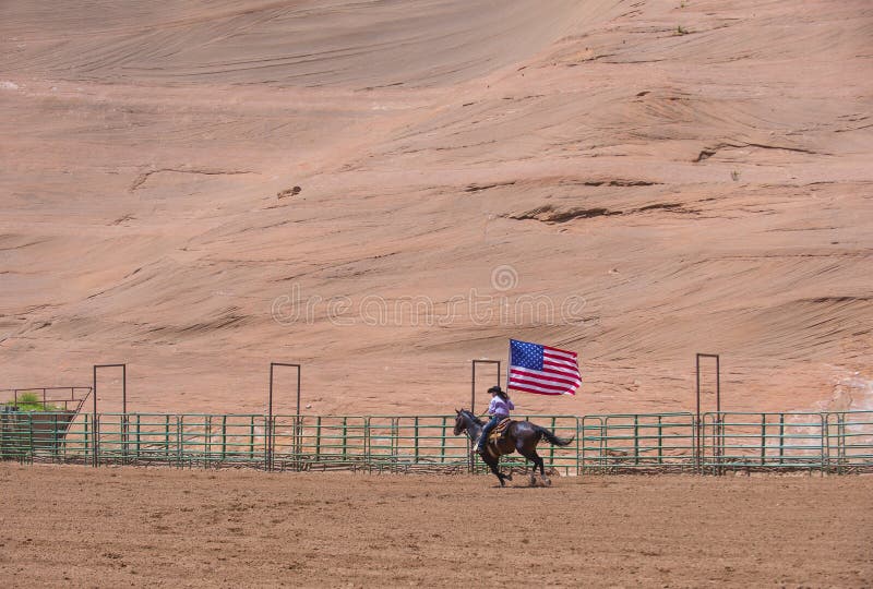 GALLUP , NEW MEXICO - AUGUST 10 : Cowgirl with American flag at the Opening Ceremony of the 92nd annual Indian Rodeo in Gallup, NM on August 10 2013. GALLUP , NEW MEXICO - AUGUST 10 : Cowgirl with American flag at the Opening Ceremony of the 92nd annual Indian Rodeo in Gallup, NM on August 10 2013