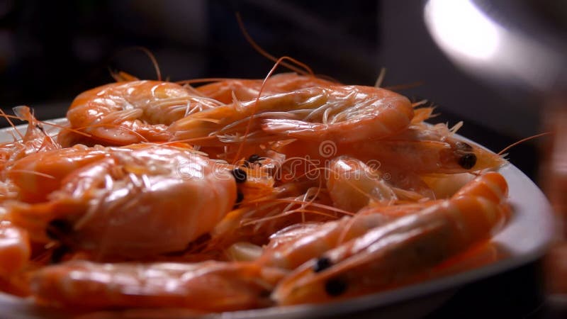 Gambas deliciosas caen sobre el plato blanco sobre el fondo negro