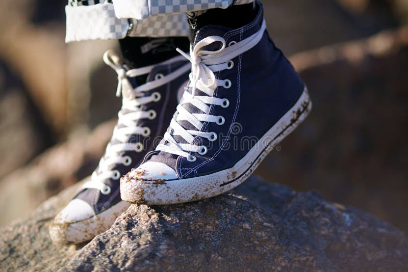 Gambe, che stanno indossando le scarpe da tennis sporche blu con i pizzi bianchi immagine stock Gambe, che stanno indossando le scarpe da tennis sporche blu con i pizzi bianchi immagine stock