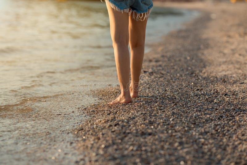 Gambe delle donne che camminano sulla spiaggia al tramonto immagini stock Gambe delle donne che camminano sulla spiaggia al tramonto immagini stock