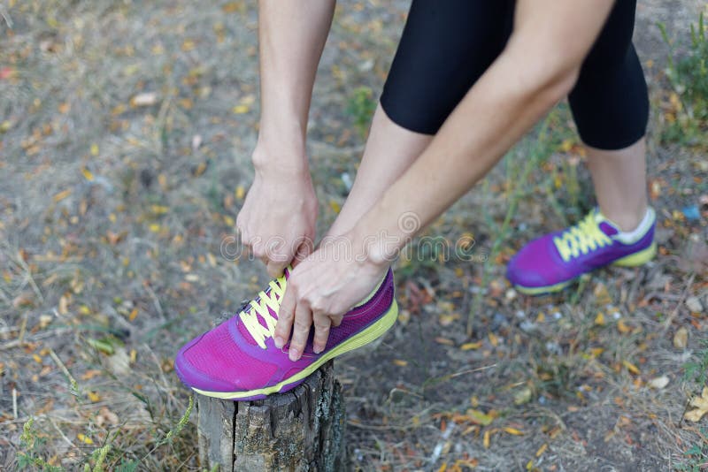 Gambe femminili Donna in scarpe da tennis lilla luminose dei legami neri degli abiti sportivi con i laccetti della calce, prepara immagine stock Gambe femminili Donna in scarpe da tennis lilla luminose dei legami neri degli abiti sportivi con i laccetti della calce, prepara immagine stock