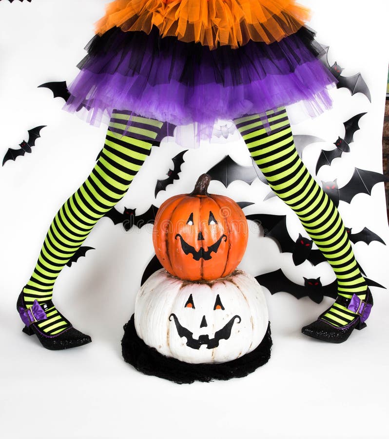 Gambe a strisce nere verdi divertenti di una bambina con il costume di Halloween di una strega con le scarpe della strega e la zu fotografie stock Gambe a strisce nere verdi divertenti di una bambina con il costume di Halloween di una strega con le scarpe della strega e la zu fotografie stock
