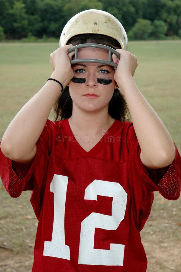 Young woman holding football and helmet. War paint. Young woman holding football and helmet. War paint.