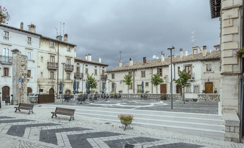 Cityscape with old picturesque houses on Fontana square and its decorated marble paving at historical town, shot in bright cloudy light  at Pescocostanzo, L`Aquila, Abruzzo, Italy. Cityscape with old picturesque houses on Fontana square and its decorated marble paving at historical town, shot in bright cloudy light  at Pescocostanzo, L`Aquila, Abruzzo, Italy