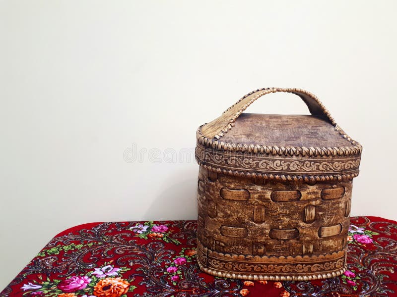 Old Russian folk style. A basket of birch bark stands on a Pavlovoposad red scarf on a white background. Old Russian folk style. A basket of birch bark stands on a Pavlovoposad red scarf on a white background.