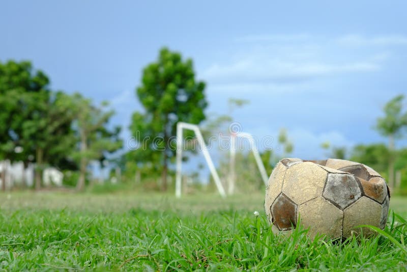 Gammal deflaterad fotbollboll, gammal deflaterad fotboll på det gröna gräset arkivbild Gammal deflaterad fotbollboll, gammal deflaterad fotboll på det gröna gräset arkivbild