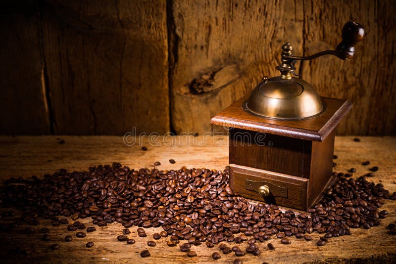 Gammal kaffekvarn med nya grillade bönor på lantlig gammal tappningekbakgrund royaltyfri bild Gammal kaffekvarn med nya grillade bönor på lantlig gammal tappningekbakgrund royaltyfri bild