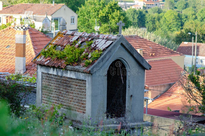 Gammal stenkapel med mossbart tak och korsning i Medelhavsbyn övergiven shrine royaltyfri foto