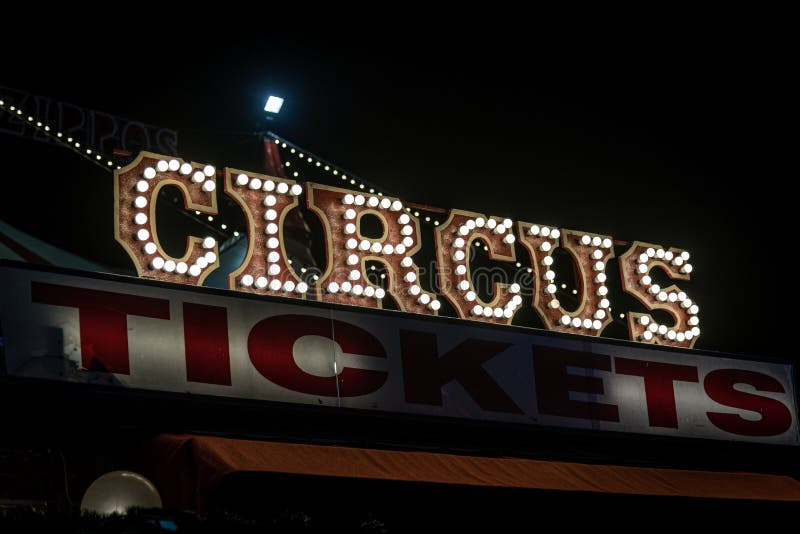 Gammal svagt upplyst cirkusskylt med glödlampor i mörker över ett biljettställ Typiskt utseende på en cirkus Begreppet arkivfoton