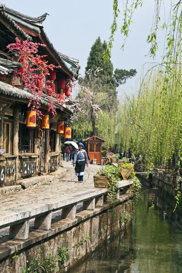 A Naxi woman walks down the narrow streets of Old Town Lijiang in Yunnan province in China. A Naxi woman walks down the narrow streets of Old Town Lijiang in Yunnan province in China.
