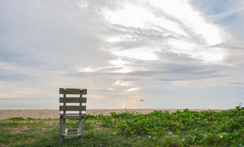 Gammal trävit stol på stranden på soluppgångtid arkivfoto Gammal trävit stol på stranden på soluppgångtid arkivfoto
