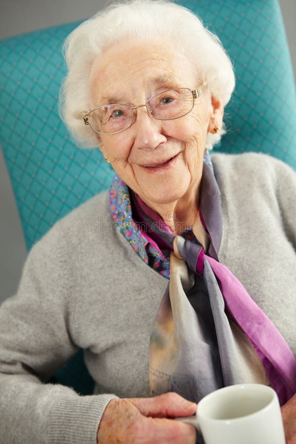 Gammalare kvinna som ser bekväm dricka tea royaltyfri foto Gammalare kvinna som ser bekväm dricka tea royaltyfri foto