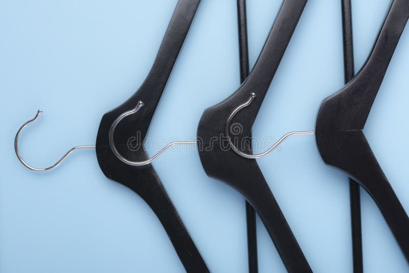 Ganci neri per modo del guardaroba dei vestiti su fondo blu Copi lo spazio immagini stock Ganci neri per modo del guardaroba dei vestiti su fondo blu Copi lo spazio immagini stock