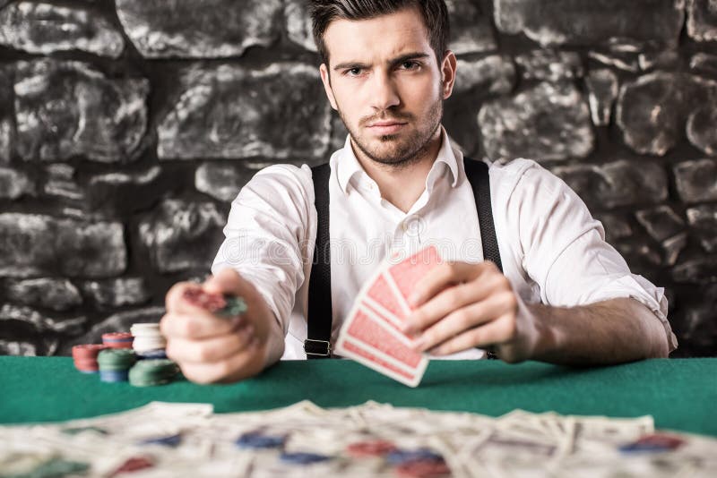 View of young, confident, gangster man in shirt and suspenders, while he's playing poker game. View of young, confident, gangster man in shirt and suspenders, while he's playing poker game.