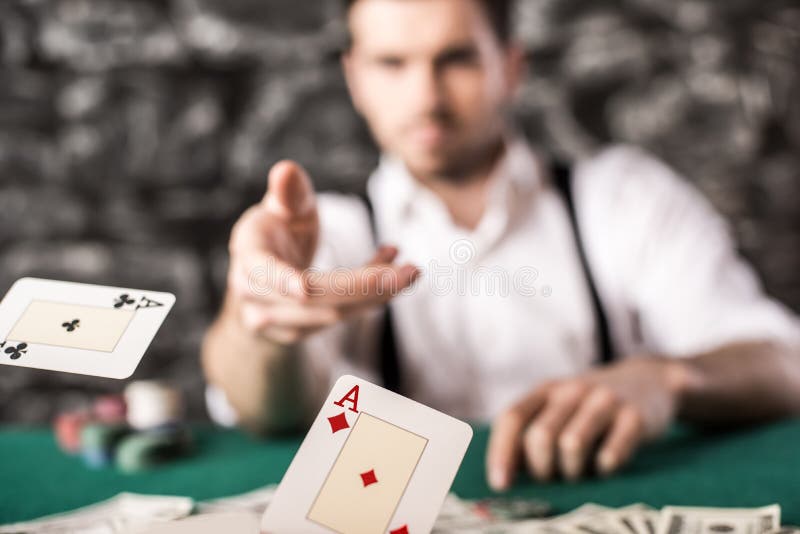 Young, confident, gangster man in shirt and suspenders, is throwing his cards on poker table, while he's playing poker game. Young, confident, gangster man in shirt and suspenders, is throwing his cards on poker table, while he's playing poker game.