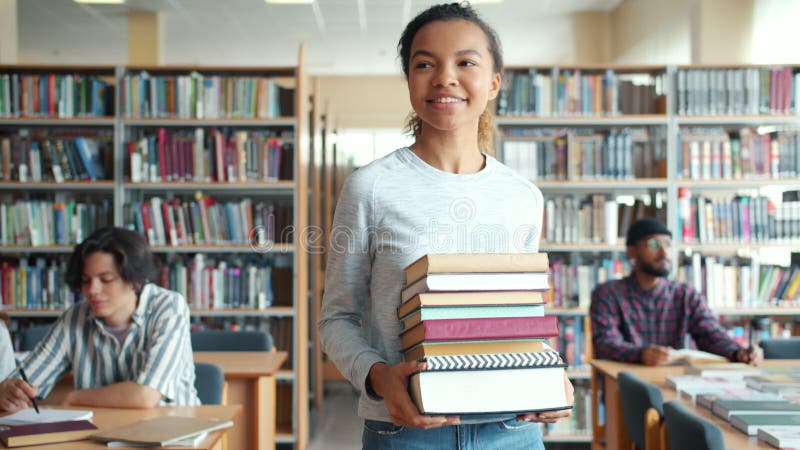 Ganska blandad racerelev med böcker som går i leende bibliotek stock video