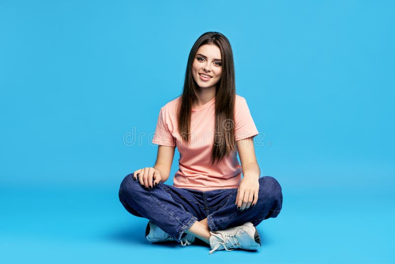 Ganska vacker ung kvinna på studion som sitter på golvet. royaltyfri fotografi