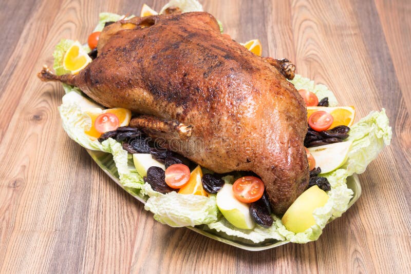 Goose roasted with apples and prunes on a platter. Goose roasted with apples and prunes on a platter