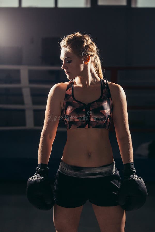 Gants de port de boxeur féminin posant dans le studio de boxe images stock Gants de port de boxeur féminin posant dans le studio de boxe images stock