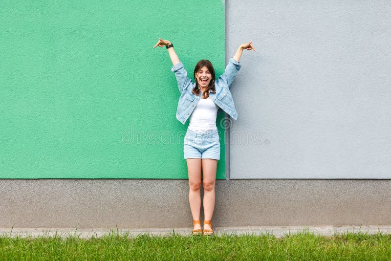 Ganzaufnahme der aufgeregten Schönheit in der zufälligen Jeansdenimart in der Sommerzeitstellung und des Zeigens auf Grün und Lic stockfotos Ganzaufnahme der aufgeregten Schönheit in der zufälligen Jeansdenimart in der Sommerzeitstellung und des Zeigens auf Grün und Lic stockfotos