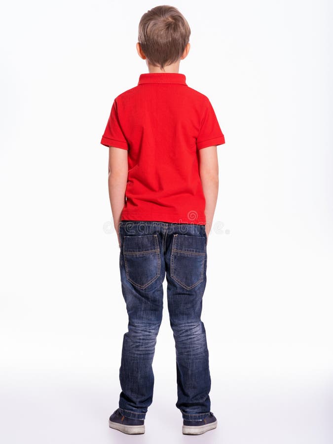 Ganzaufnahme einer Kinderstellung zurück in die Kamera. Kind steht am Studio. kleiner Junge gekleidet im roten T-Shirt und Jeans lizenzfreies stockfoto