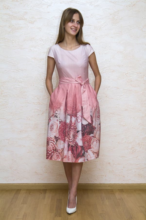 Ganzaufnahme eines schönen jungen glücklichen überzeugten Mädchens mit dem langen blonden Haar, das im Sommerkleid mit rosa Blume lizenzfreie stockfotos Ganzaufnahme eines schönen jungen glücklichen überzeugten Mädchens mit dem langen blonden Haar, das im Sommerkleid mit rosa Blume lizenzfreie stockfotos