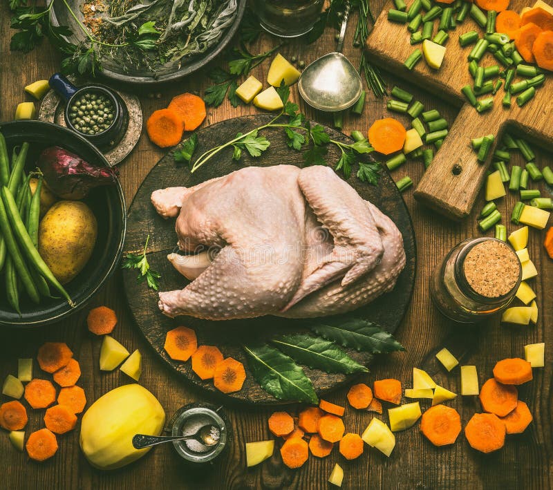 Ganzes Huhn mit verschiedenen gesunden kochenden Bestandteilen für Suppe oder Vorrat: gehacktes Gemüse, Kräuter und Gewürze auf r lizenzfreies stockbild