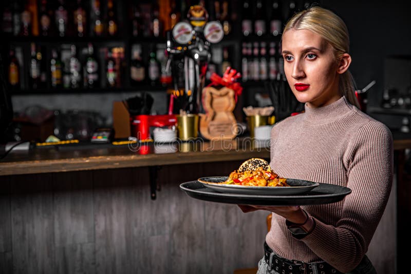 Garçonete bonita servindo grupo de amigas com comida no restaurante