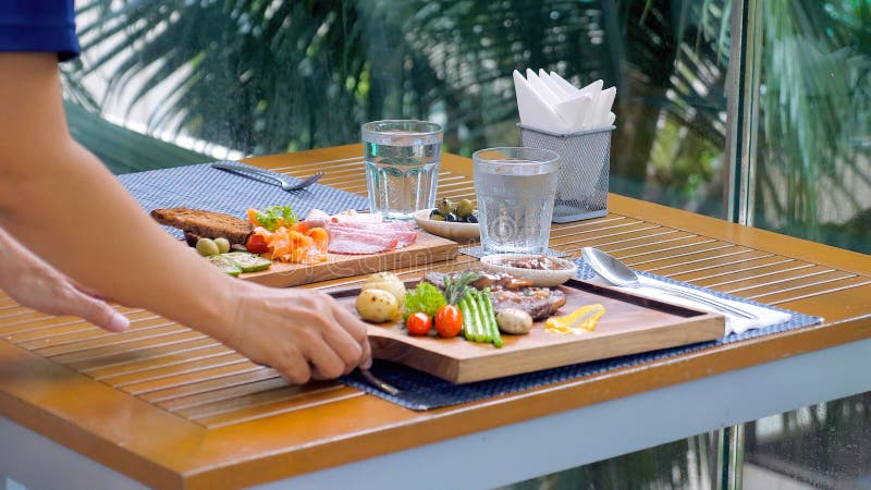 A Garçonete Do Restaurante Traz Um Prato Delicioso Com Bife Para a Mesa  Foto de Stock - Imagem de jogo, carne: 273523240