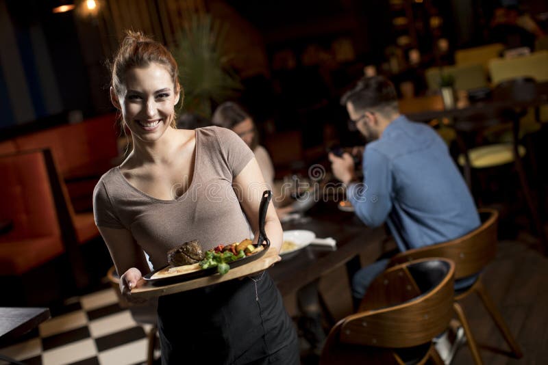 Garçonete bonita servindo grupo de amigas com comida no restaurante