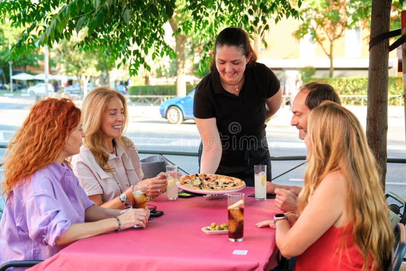 Garçonete bonita servindo grupo de amigas com comida no