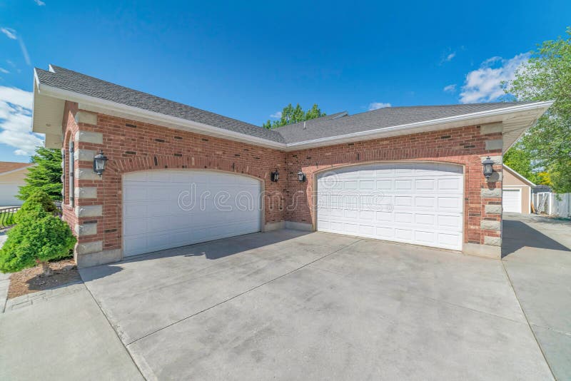 Garage with two arched white doors and red brick wall against sunny blue sky