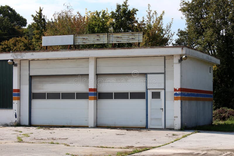 Garaje del servicio del coche abandonado por los dueños después de salir del negocio con las señales de neón quebradas en la fach imagen de archivo libre de regalías Garaje del servicio del coche abandonado por los dueños después de salir del negocio con las señales de neón quebradas en la fach imagen de archivo libre de regalías