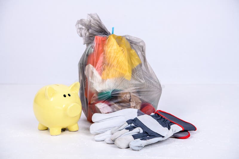 Garbage bag with defferent content with yellow piggy bank and work gloves
