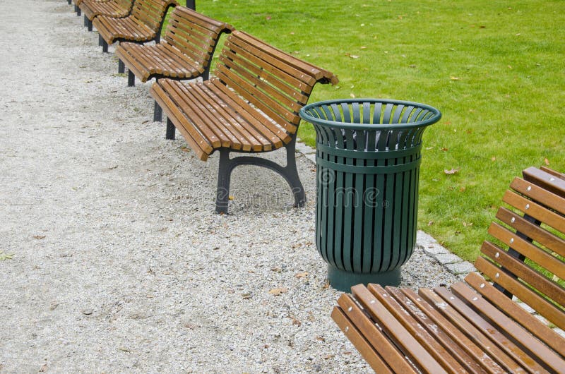 Garbage bin and wooden bench in city park