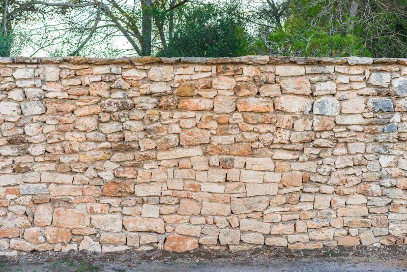 Garden stone wall texture with sidewalk and trees background