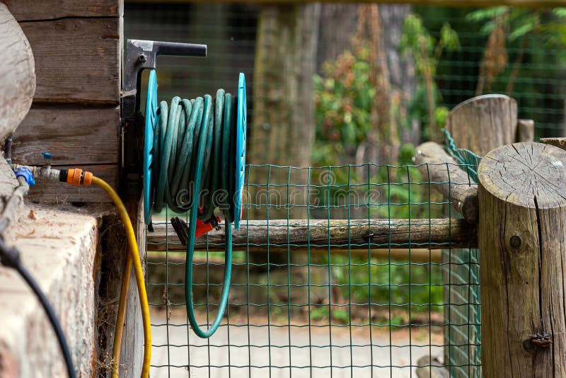 Garden Water Hose Reel Hung on the Wooden Wall of a Log Farm