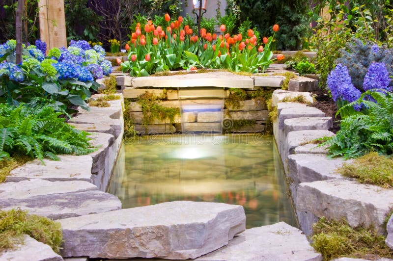 A designed garden with different flowers, a waterfall and a stone pond. Man made waterfall stock images, royalty-free photos and pictures