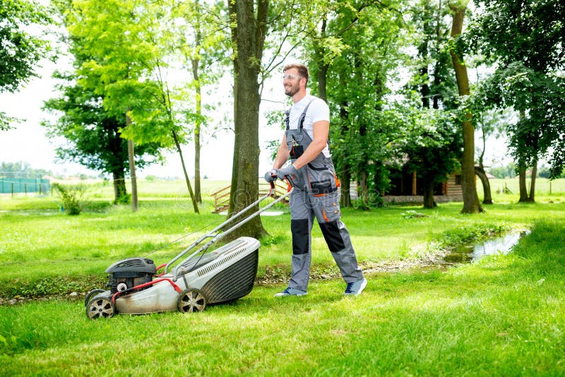 Gardener equipado com cortador de relva no trabalho