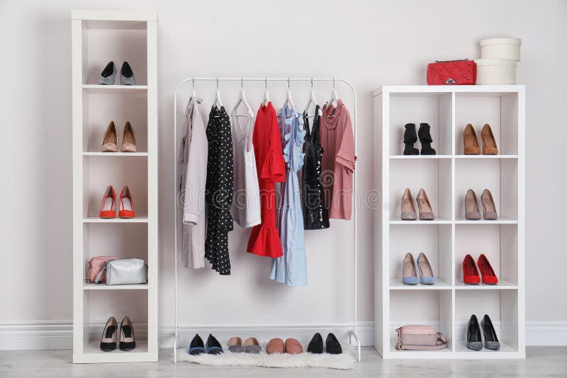 Garderobenregale mit unterschiedlichen stilvollen Schuhen und Kleidung zuhause