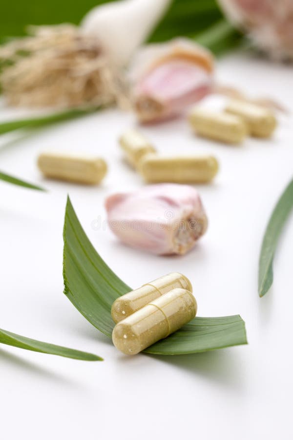 Closeup of garlic extract pills and fresh garlic leaves and cloves best suited for health, anti-cholesterol and alternative medicine ads. Green herbal drug medicine stock images, royalty-free photos and pictures