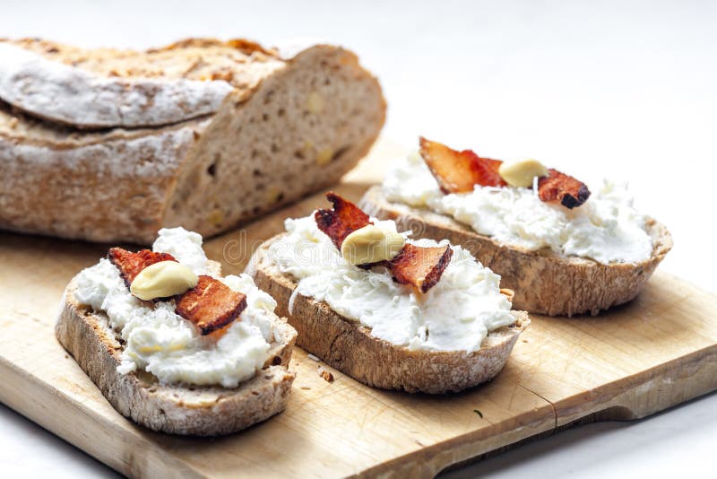 garlic spread on slice of bread served with bacon, grated cheese and mustard