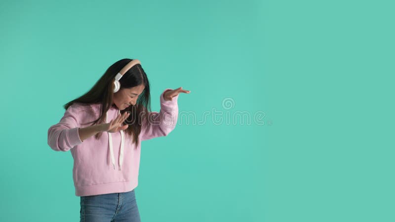 Garota asiática alegre nos fones de ouvido movendo-se para música