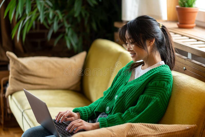 Garota asiática de cabelo escuro trabalhando em laptop e sorrindo imagem de stock royalty free